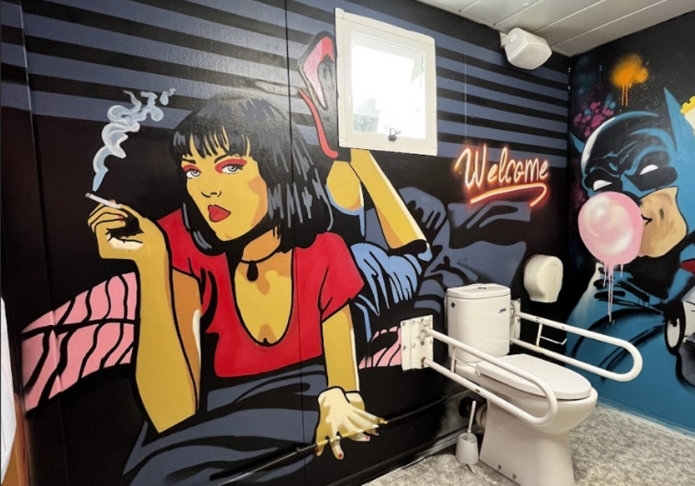 Graffitis de batman y mujer en un baño